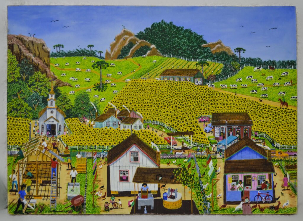 Pintura naïf de Marcelo Schimaneski intitulada "Recanto Bela Vista". Paisagem rural com campos de girassóis amarelos, casas coloridas, uma pequena igreja branca, vacas pastando e morros cobertos de vegetação ao fundo.